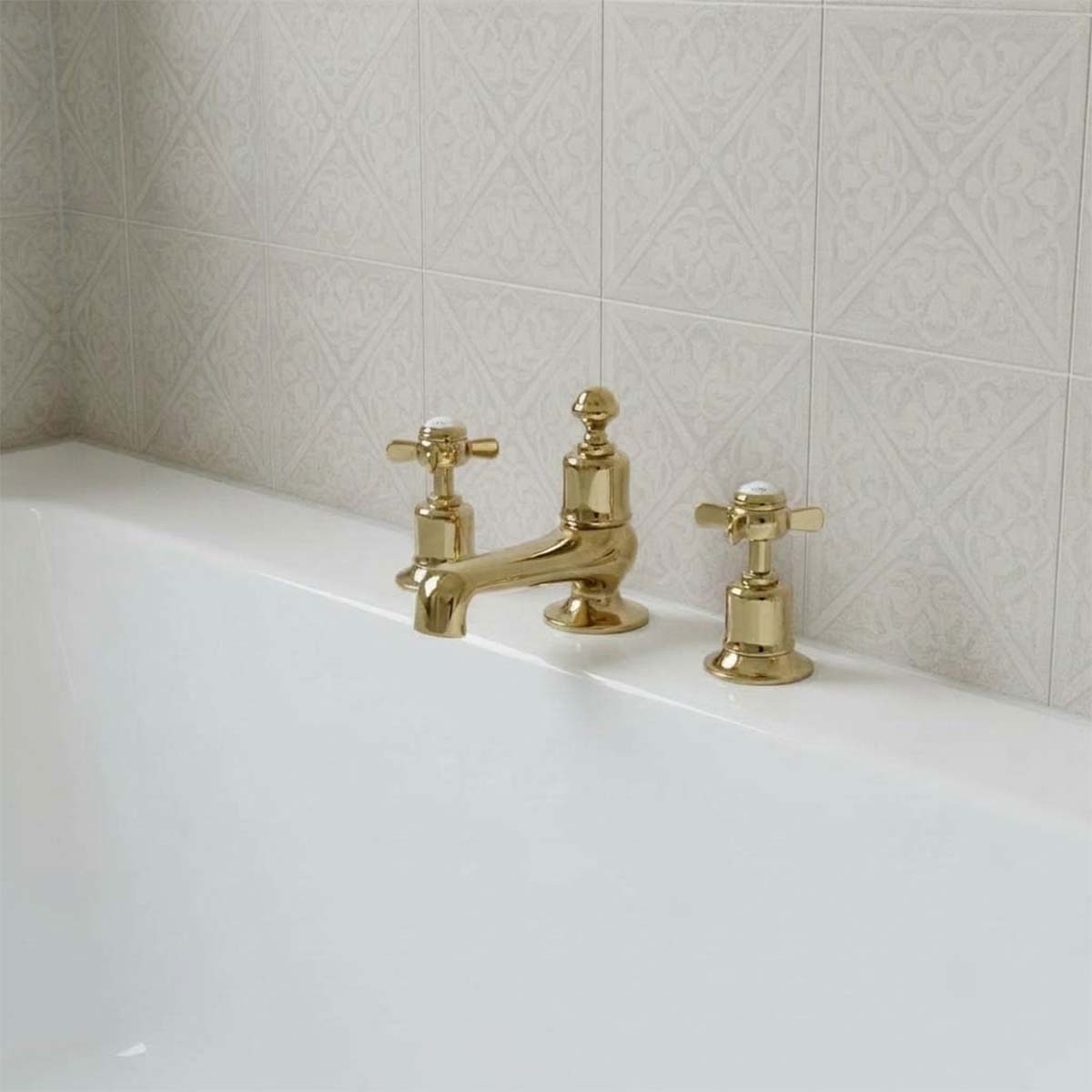 gold three-hole bath tap with crosshead handles installed on a bath edge